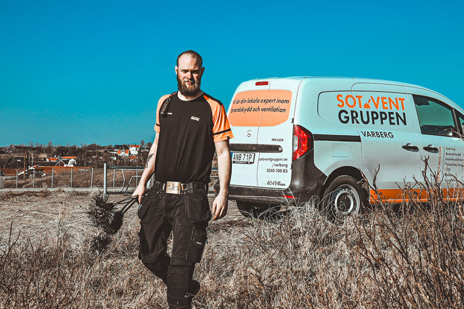 Sotare kommer gående över tort gräs, bil parkerad i bakgrunden